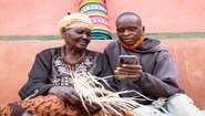 Zwei Landwirte in Uganda verwendet das Smartphone um Landarbeiter zu finden, 2021.