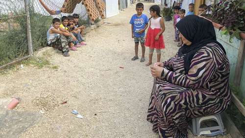 Spenden Sie jetzt für den Libanon! Bild: Eine Frau und mehrere Kinder sitzen und stehen auf der Straße.