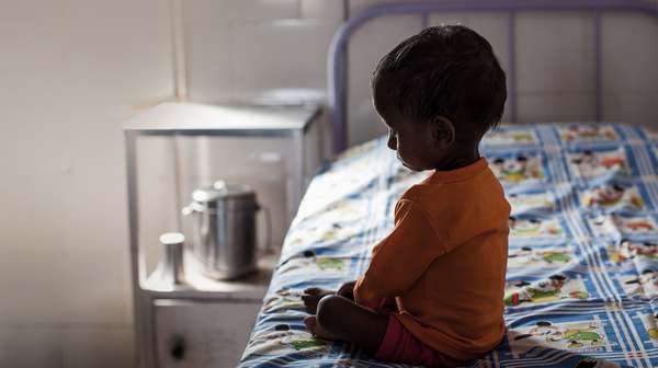 Ein Junge seitzt auf einem Krankenhausbett, Indien 2021.