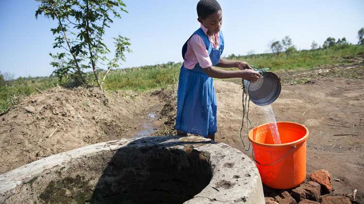 Chimwemwe holt Wasser am neu gebauten Brunnen der Schule
