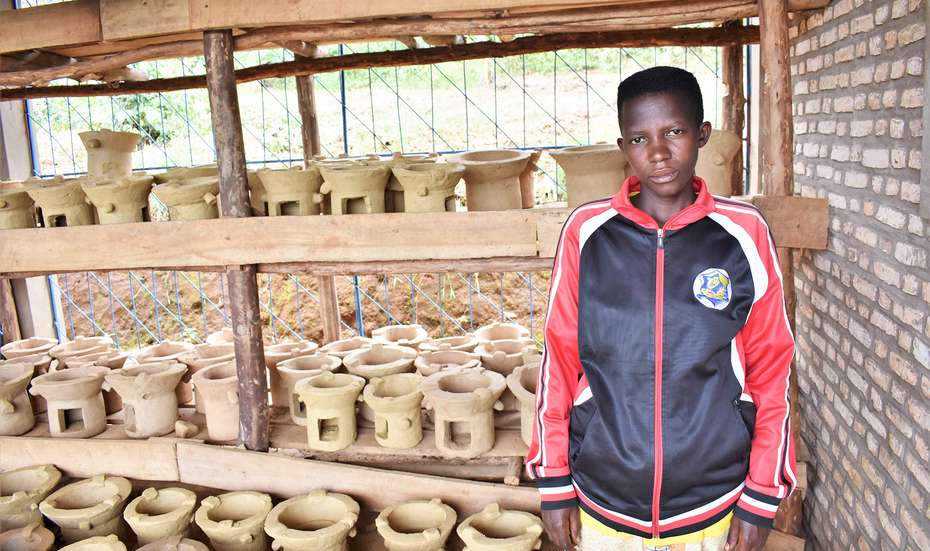 Eine junge Frau zeigt die neuen, effizienten Öfen, die sie baut, Burundi 2021.