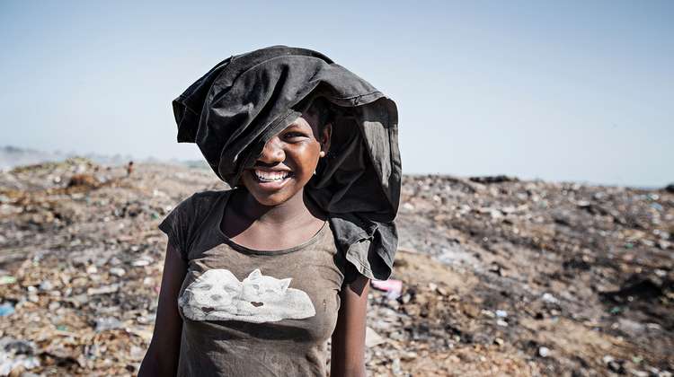 Jetzt für Madagaskar spenden. Bild: Eine Frau mit einem Kleidungsstück auf dem Kopf lächelt in die Kamera.