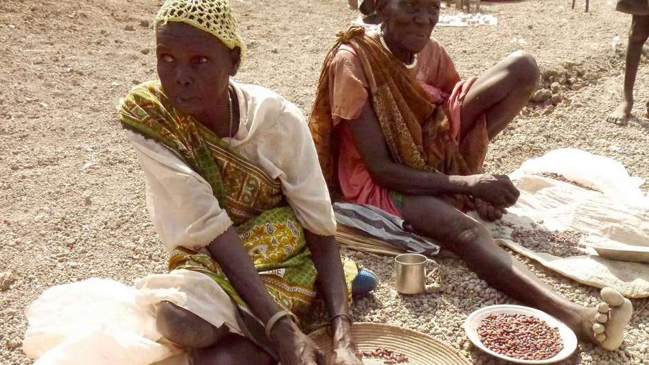 Zwei Frauen sitzen vor Nahrungsmitteln auf dem Boden.