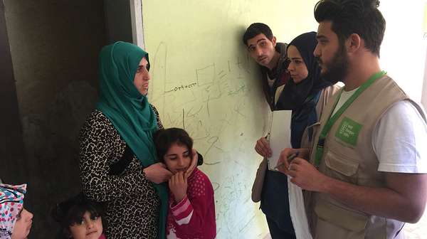 Eine Flüchtlingsfamilie n der Türkei spricht mit einem Mitarbeiter der Welthungerhilfe