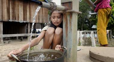 Girl fetching water at water well. 