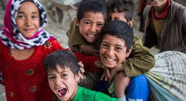 Eine Gruppe lachender Kinder in einer provisorischen Schule in einem Flüchtlingslager in Afghanistan