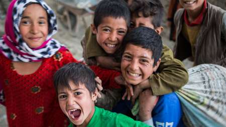 Eine Gruppe lachender Kinder in einer provisorischen Schule in einem Flüchtlingslager in Afghanistan