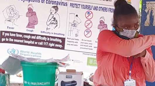 Eine Frau mit Mundschutz demonstriert Schutzmaßnahmen zu Corona.