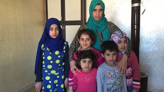 Eine Spende für syrische Flüchtlinge. Bildbeschreibung: Eine Familie in einem kleinen Raum.