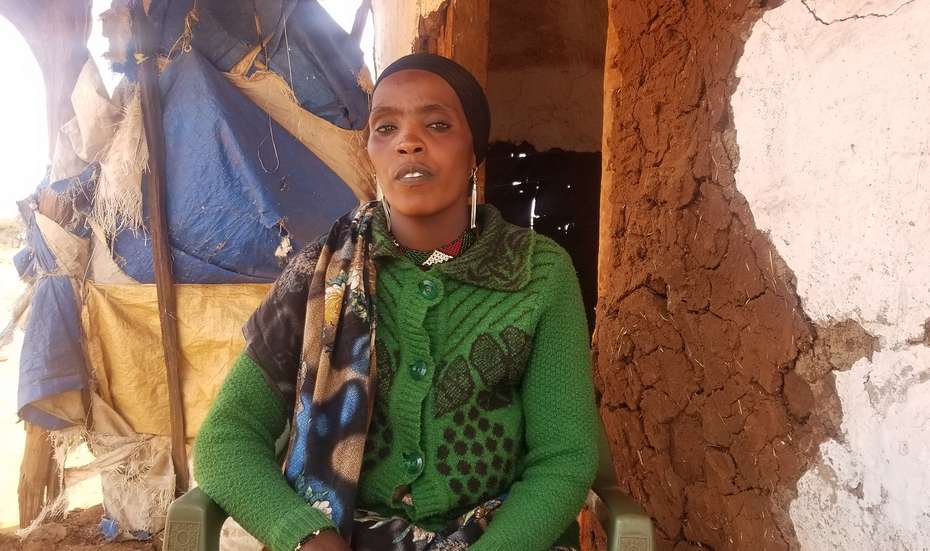 Eine Frau aus Äthiopien sitzt vor ihrem Haus und schaut in die Kamera.