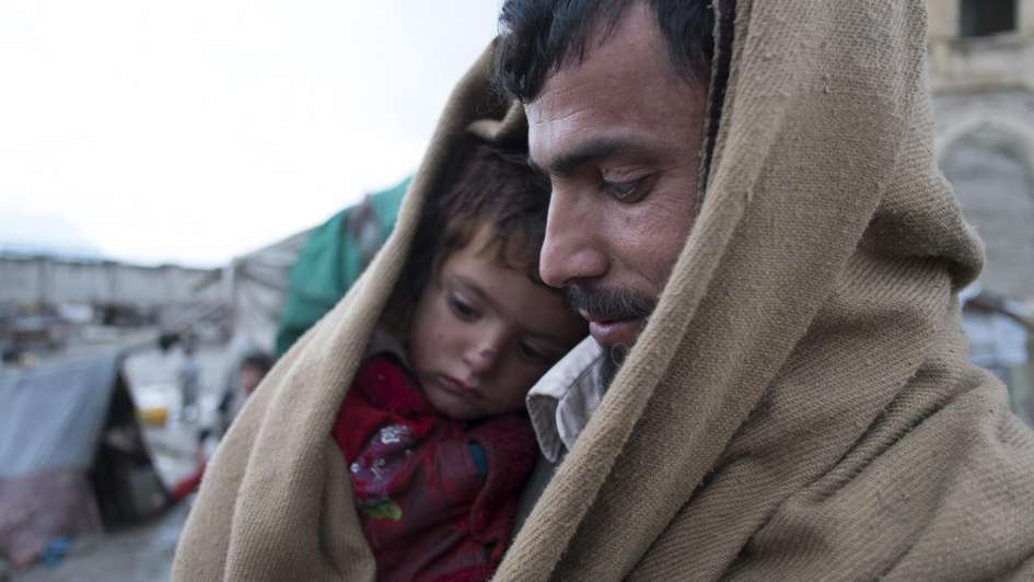 Vater mit Sohn in eine Decke gehüllt im Flüchtlingscamp