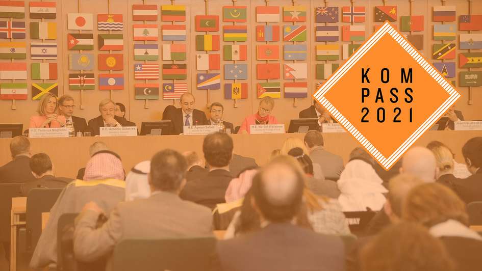 FAO-Treffen in Rom – Federica Mogherini, António Guterres und weitere Politiker*innen sitzen auf einem Podium. Im Hintergrund sind Flaggen vieler verschiedener Länder zu sehen. Rechts oben ist das Kompass 2021 Logo. 