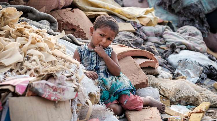 Ein Mädchen sitzt auf einem Haufen von Schaumstoff Resten und alten Matratzen.