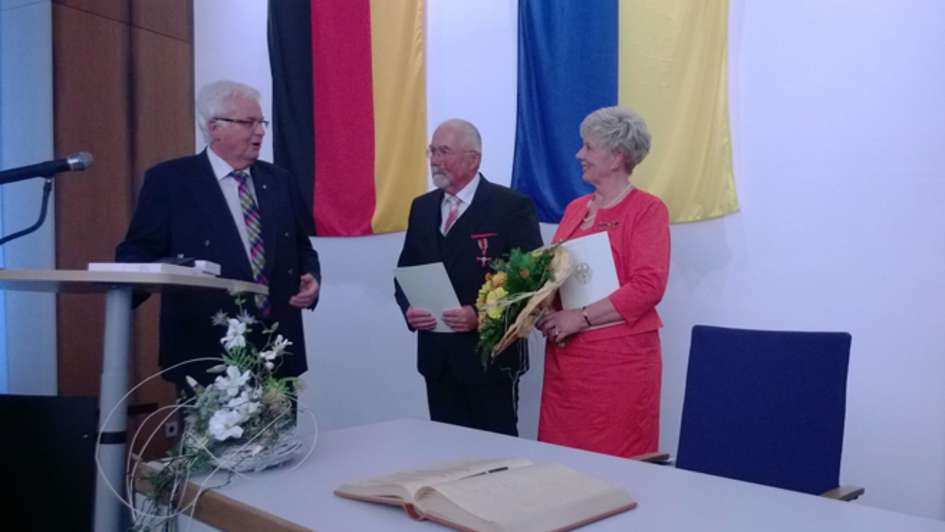 Landrat Friedhelm Spieker (links) überreicht Friedhelm und Editha Henkst die beiden Bundesverdienstkreuze am Bande.