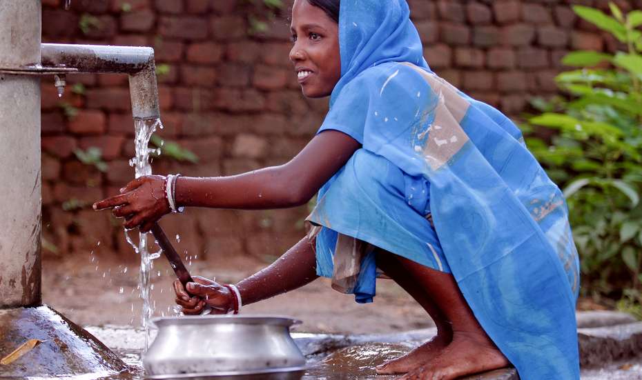 WASH-Projekte: Ein Mädchen wäscht an einem Brunnen, Indien