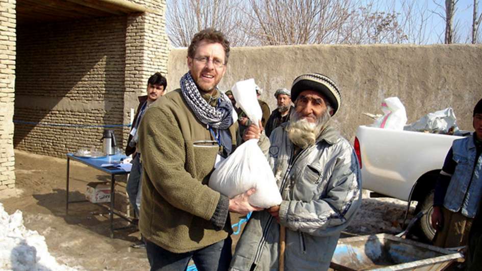 Mann übergibt einen Sack mit Lebensmitteln an einen älteren Herren