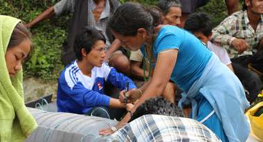 Eine Frau beschriftet Hilfsgüter wie Decken, Matten und Nahrung