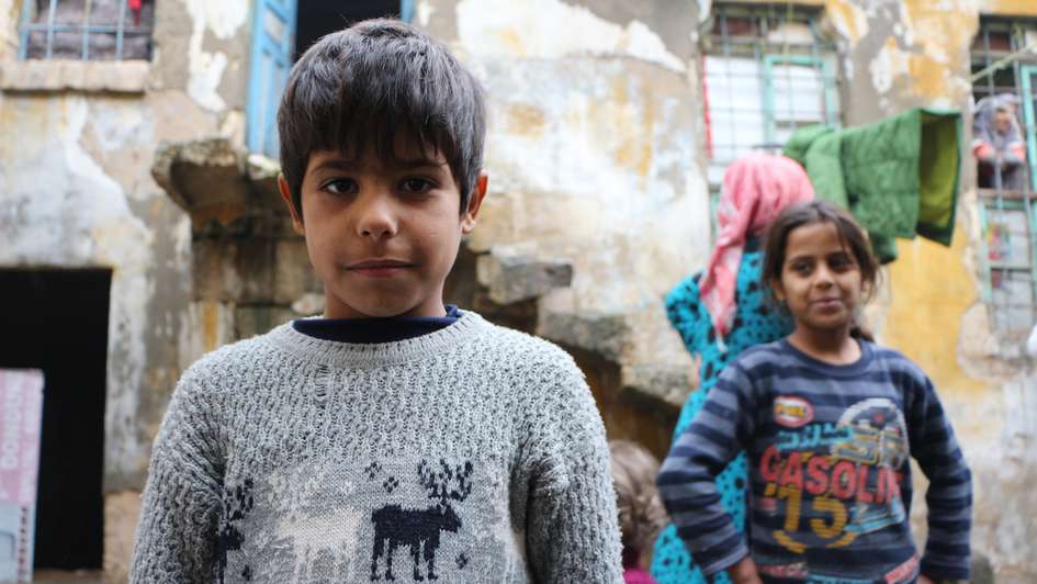 Portraitaufnahme von 2 Kindern vor ihrem Wohnhaus im Syrienkrieg