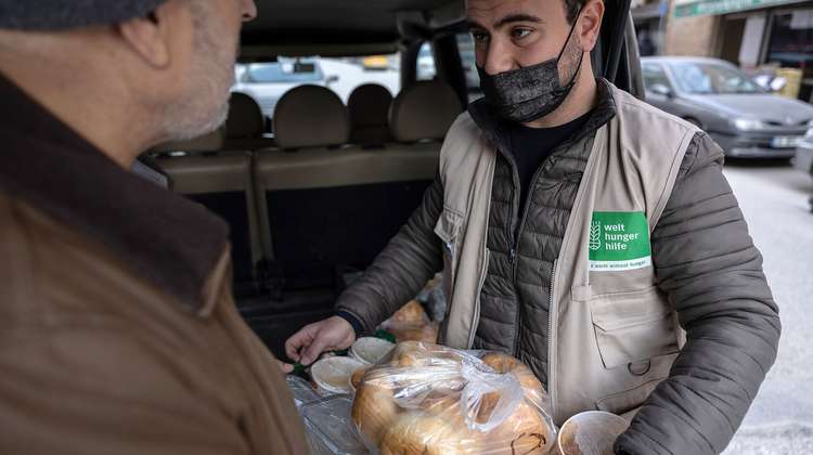 Ein Mitarbeiter der Welthungerhilfe überreicht einem Familienvater ein Paket mit frischen Lebensmitteln