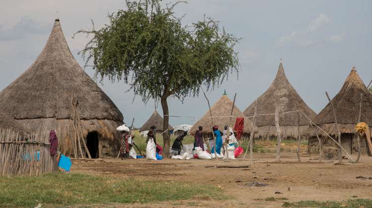 An einer Verteilungsstelle für Nahrungsmittel der Welthungerhilfe in Südsudan sitzen Menschen auf ihren Lebensmitteln, bevor sie es nach Hause tragen, 2017