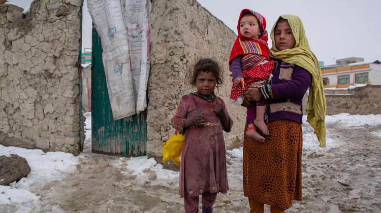 Eine Frau mit ihren beiden Kindern in einem Camp im Winter – eine Vielzahl an Fluchtursachen in Afghanistan hat sie dazu bewegt, ihr Land zu verlassen.