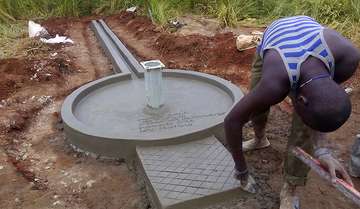 Ein Mann verputzt einen neu entstandenen Brunnen