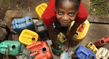 Mädchen am Brunnen mit Wasserkanistern