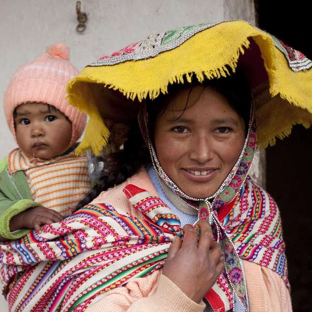 Eine Frau aus Peru trägt ihr Kind auf dem Rücken.
