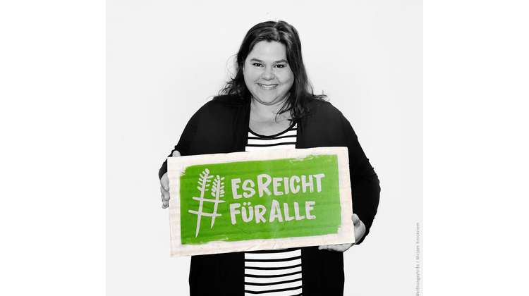Schauspielerin Nadine Wrietz hält ein Schild mit dem Welthungerhilfe-Hashtag #EsReichtFürAlle.