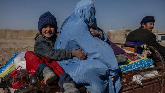 Ein Mädchen sitzt mit ihrer Mutter auf der Ladefläche eines Wagens, Afghanistan 2022.