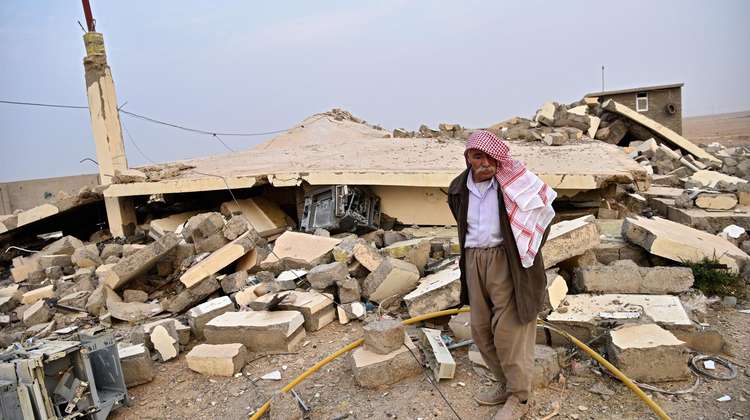 Ein Bauer steht vor seinem zerstörten Haus