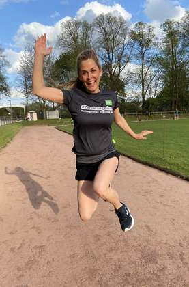 Tanja Lanäus hat das #ZeroHungerRun-Shirt an und springt in die Höhe