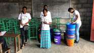 Mitarbeiter der Welthungerhilfe mit Eimern und Handwasch-Ständern in einer Schule