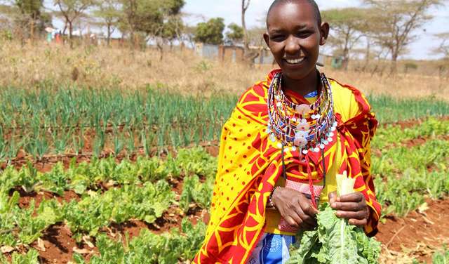 Eine Frau steht mit ihrer Ernte auf dem Feld, Kenia 2020. 