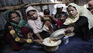 Eine Gruppe von Rohingya Flüchtlingen im Distrikt Cox's Bazar in Bangladesch hat von der lokalen Bevölkerung Essen erhalten. Von links nach rechts: Roseda Begom, 40 Jahre, Tochter Kismat Ara, 16 Jahre mit Baby Raeshma, 3 Monate. Kismats Mann wurde von der Armee in Myanmar verhaftet und ist seitdem verschollen.