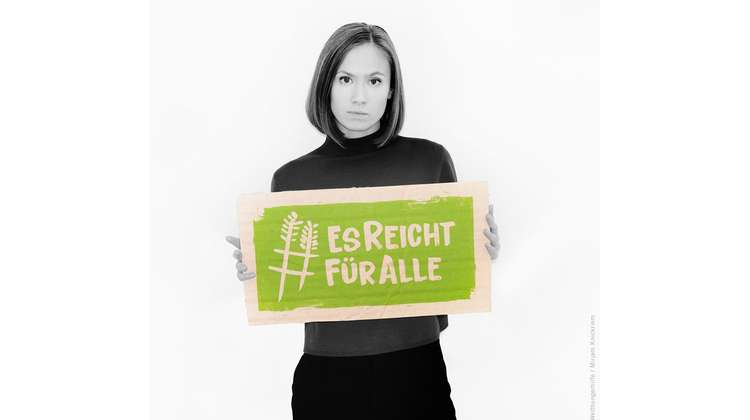 Schauspielerin Alina Levshin hält ein Schild mit dem Welthungerhilfe-Hashtag #EsReichtFürAlle.
