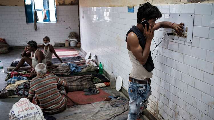 Ein junger Mann steht an der Wand und telefoniert mit einem Handy.