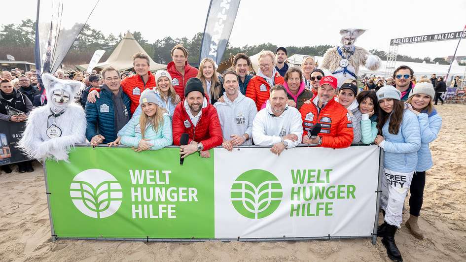 Gruppenfoto prominenter Teilnehmer*innen am Baltic Lights 2024 vor einem Banner der Welthungerhilfe