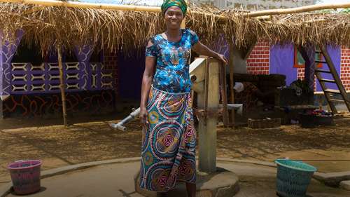 Eine Frau steht vor der Wasserpumpe, Liberia 2020.