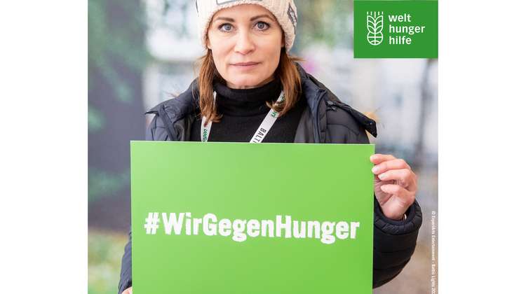Anja Kling hält ein grünes Schild, darauf steht: #WirGegenHunger