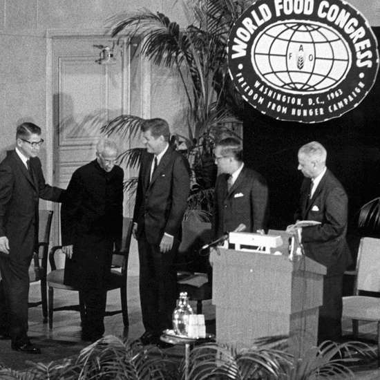Schwarzweiß-Foto der fünf Männer, im Hintergrund hängt ein Schild "World Food Congress"