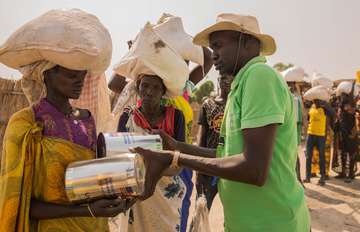 Ein Mitarbeiter der Welthungerhilfe überreicht einer Frau Hilfsgüter.