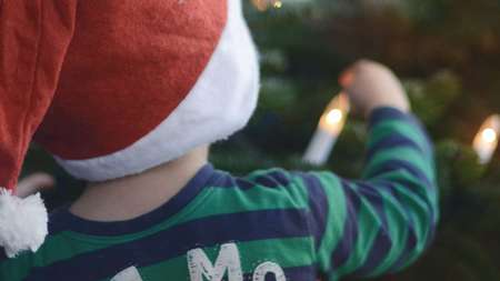 Anlassspende zu Weihnachten: Zwei Kinder mit Weihnachtsmützen vor dem Tannenbaum