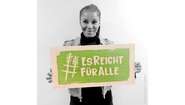 Schauspielerin Liz Baffoe hält ein Schild mit dem Welthungerhilfe-Hashtag #EsReichtFürAlle.