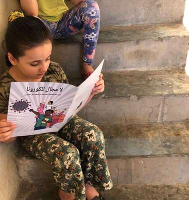 Ein Mädchen liest einen Comic auf der Treppe, Türkei 2020. 