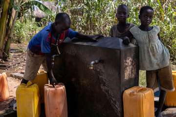 Kinder an einem Trinkwasserbrunnen in Uganda