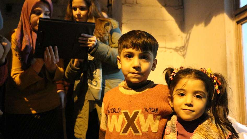 Syrische Flüchtlingskinder: Zwei im Vordergrund, zwei andere schauen sich etwas auf einem Papier an.