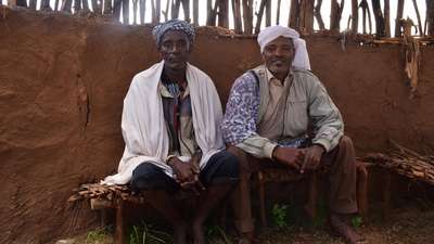 Zwei Äthiopier sitzen auf Hockern.