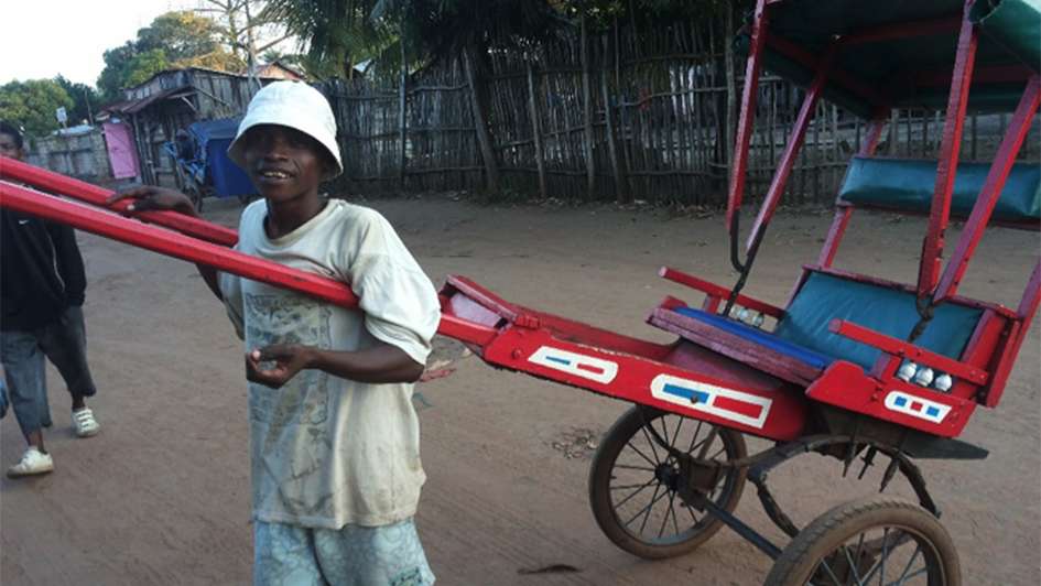 Ein Junge zieht ein Pousse-Pousse (Ein Riksha-ähnliches Taxi)