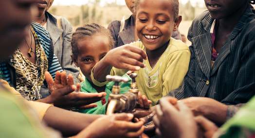 Lachende Kinder stehen um einen Wasserhahn herum und waschen sich die Hände, Äthiopien 2017.